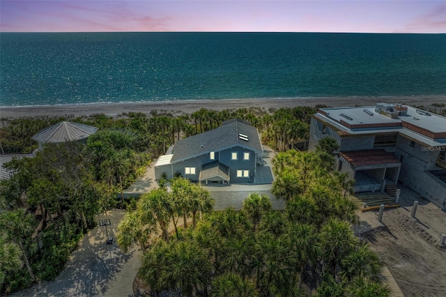 aerial view at dusk with a water view and a beach view