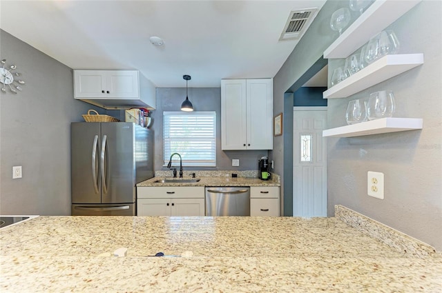 kitchen with light stone counters, stainless steel appliances, visible vents, white cabinets, and a sink