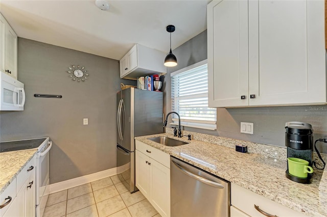 kitchen featuring pendant lighting, stainless steel appliances, light tile patterned flooring, a sink, and baseboards