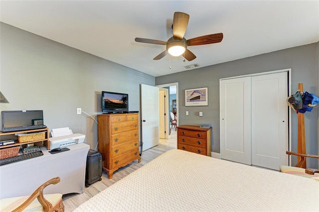 bedroom with light wood-type flooring, ceiling fan, visible vents, and a closet