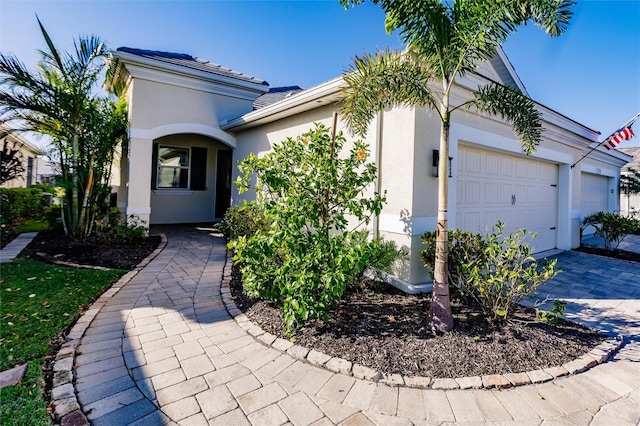 mediterranean / spanish-style home featuring decorative driveway, an attached garage, and stucco siding