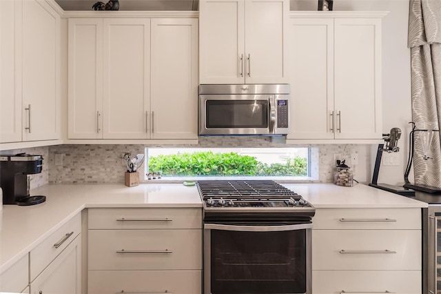 kitchen featuring light countertops, appliances with stainless steel finishes, white cabinets, and tasteful backsplash