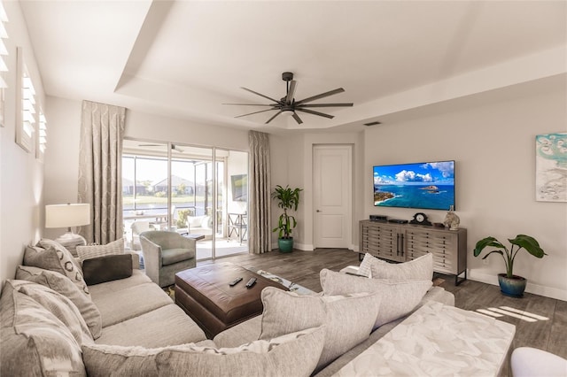 living room featuring visible vents, baseboards, a raised ceiling, ceiling fan, and wood finished floors