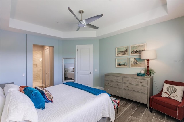 bedroom featuring ensuite bath, a raised ceiling, a ceiling fan, and wood tiled floor