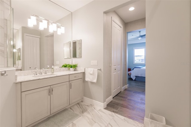 bathroom with a ceiling fan, vanity, baseboards, marble finish floor, and ensuite bath