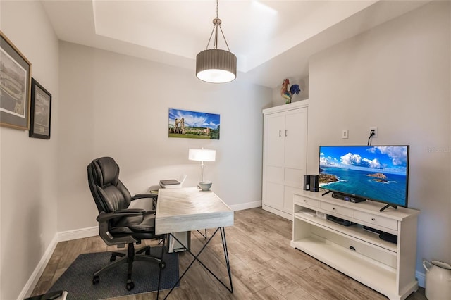 office area with a raised ceiling, wood finished floors, and baseboards