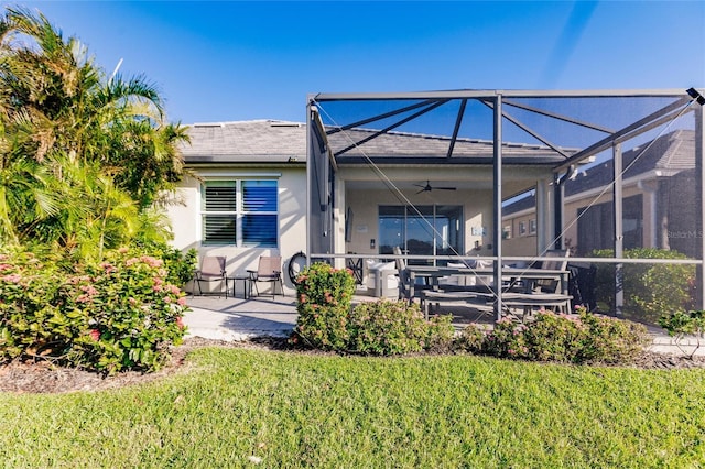 rear view of property with a patio area, ceiling fan, glass enclosure, and stucco siding