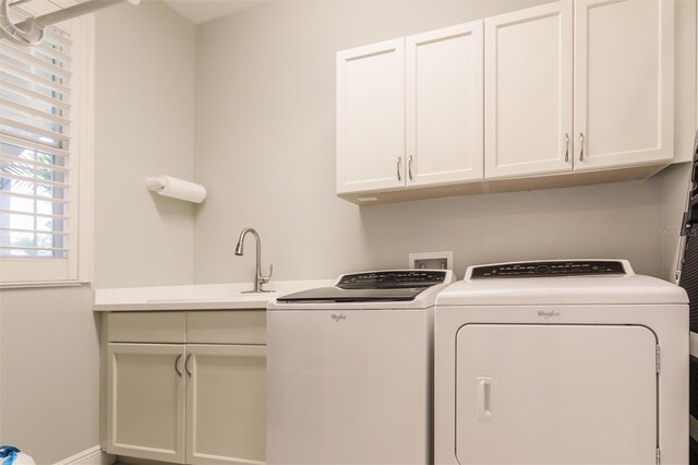 laundry room with separate washer and dryer, a sink, cabinet space, and baseboards