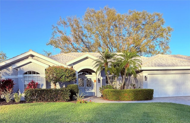 single story home featuring a garage, a front lawn, decorative driveway, and stucco siding