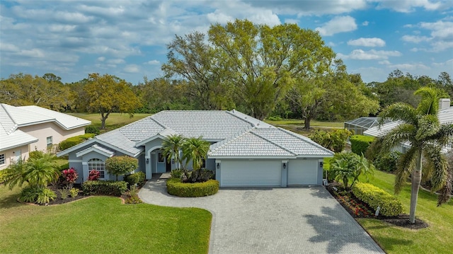 ranch-style home featuring a front lawn, a tile roof, stucco siding, decorative driveway, and a garage