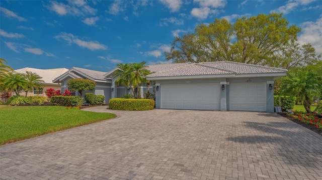 single story home featuring an attached garage, stucco siding, a front lawn, a tiled roof, and decorative driveway