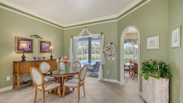 dining area featuring light tile patterned floors, baseboards, arched walkways, and crown molding