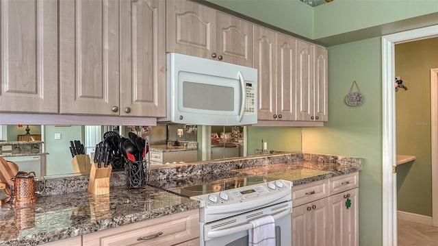 kitchen with dark stone counters and white appliances