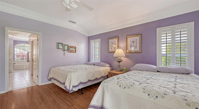 bedroom featuring wood finished floors, visible vents, ceiling fan, ornamental molding, and connected bathroom