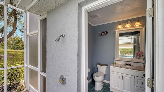 bathroom featuring tile patterned floors, visible vents, toilet, vanity, and a textured wall