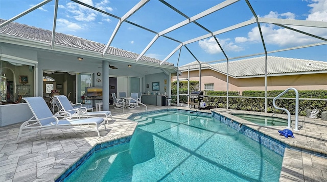 view of pool featuring a patio, a ceiling fan, a pool with connected hot tub, and a lanai