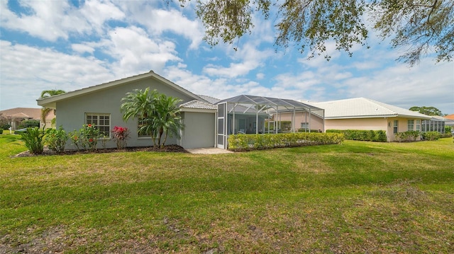 back of property with glass enclosure, a lawn, and stucco siding