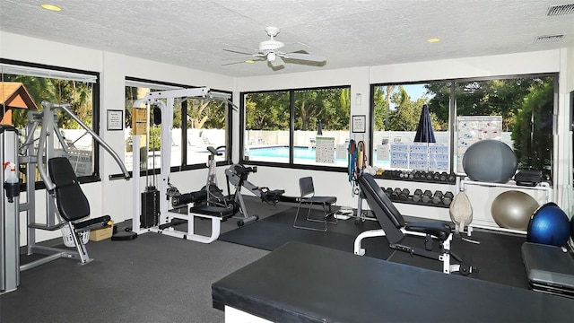 workout area featuring a ceiling fan, visible vents, and a textured ceiling