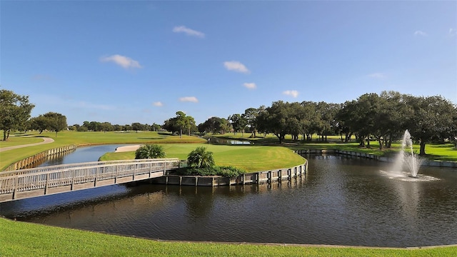 view of community featuring a yard, a water view, and golf course view