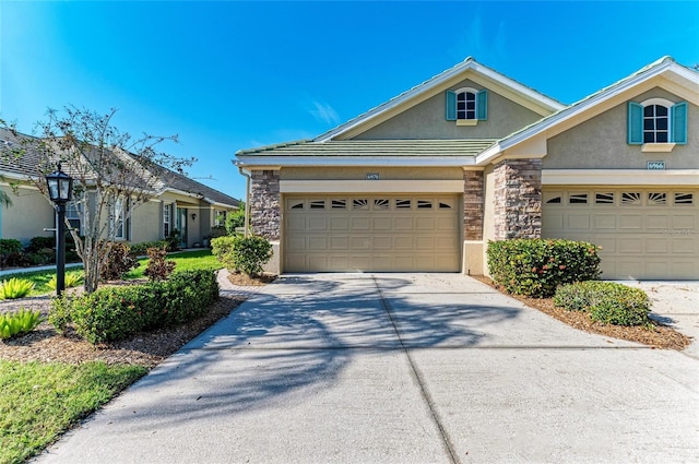 view of front of property featuring driveway, stone siding, a garage, and stucco siding