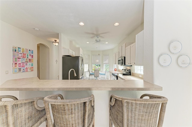 kitchen featuring stainless steel appliances, a breakfast bar, recessed lighting, and white cabinets