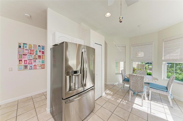 kitchen featuring light tile patterned floors, stainless steel fridge, visible vents, white cabinets, and pendant lighting