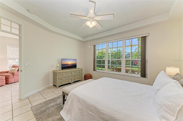 bedroom with light tile patterned floors, multiple windows, baseboards, and a raised ceiling