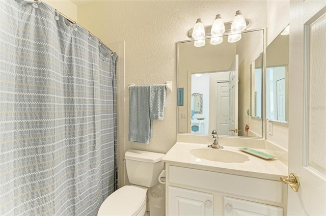 bathroom featuring a shower with shower curtain, a textured wall, vanity, and toilet