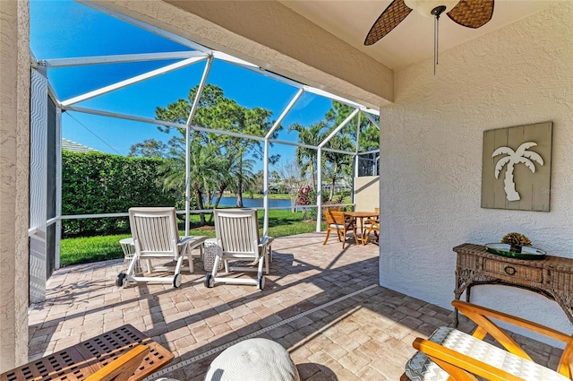 view of patio / terrace featuring a ceiling fan, a lanai, and a water view