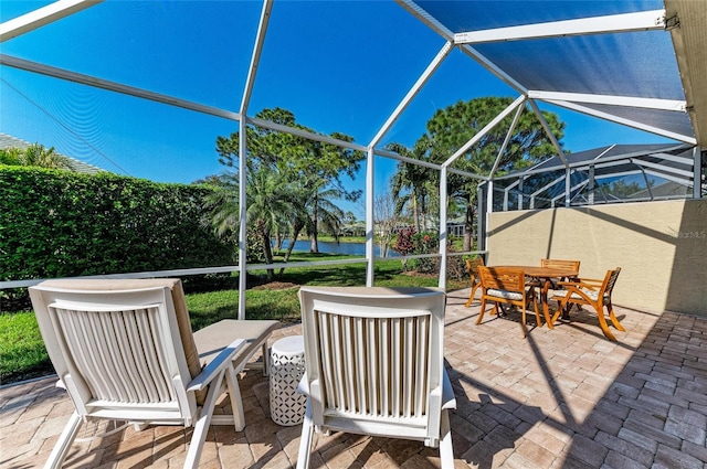 view of patio with a water view, glass enclosure, and outdoor dining area