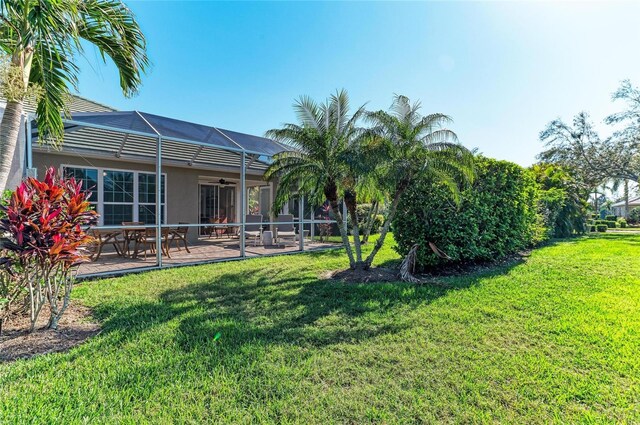 view of yard featuring a lanai, a patio area, and a ceiling fan