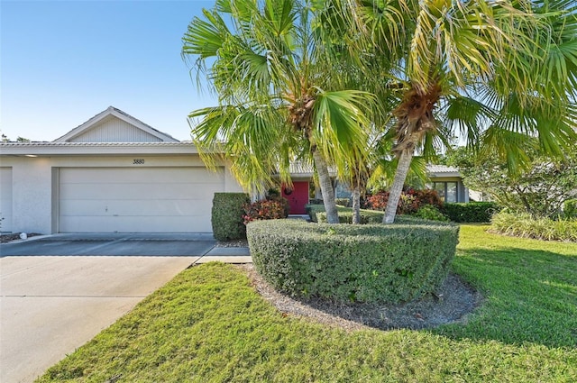 view of front of house with a garage, a front lawn, concrete driveway, and stucco siding