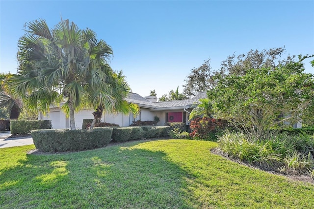 view of property hidden behind natural elements featuring a front lawn and an attached garage