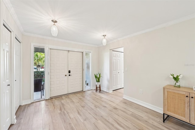 foyer entrance featuring ornamental molding, light wood-style flooring, and baseboards