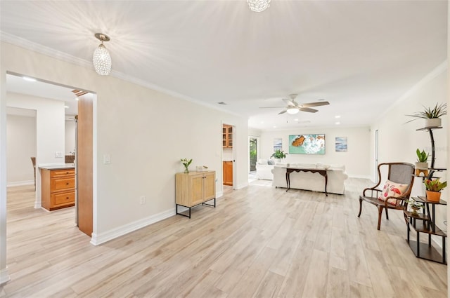 living area with baseboards, ceiling fan, light wood-type flooring, and crown molding