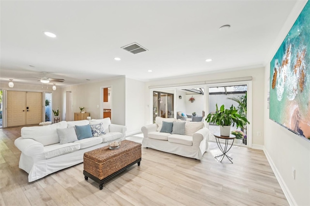 living area featuring visible vents, crown molding, baseboards, and wood finished floors