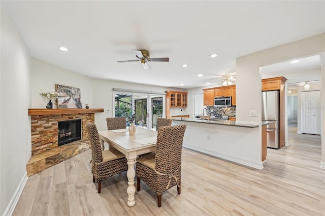 dining space featuring light wood-style floors, recessed lighting, a fireplace, and ceiling fan