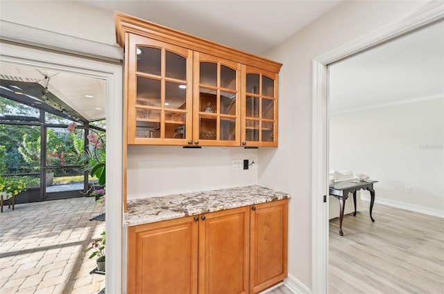 bar with light wood-style floors, a sunroom, and baseboards