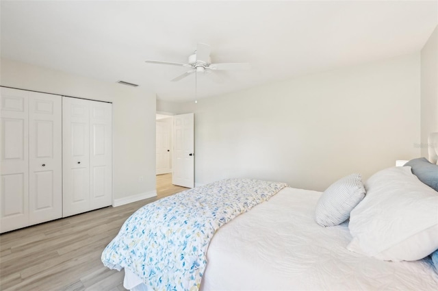 bedroom with a ceiling fan, baseboards, visible vents, light wood-style floors, and a closet