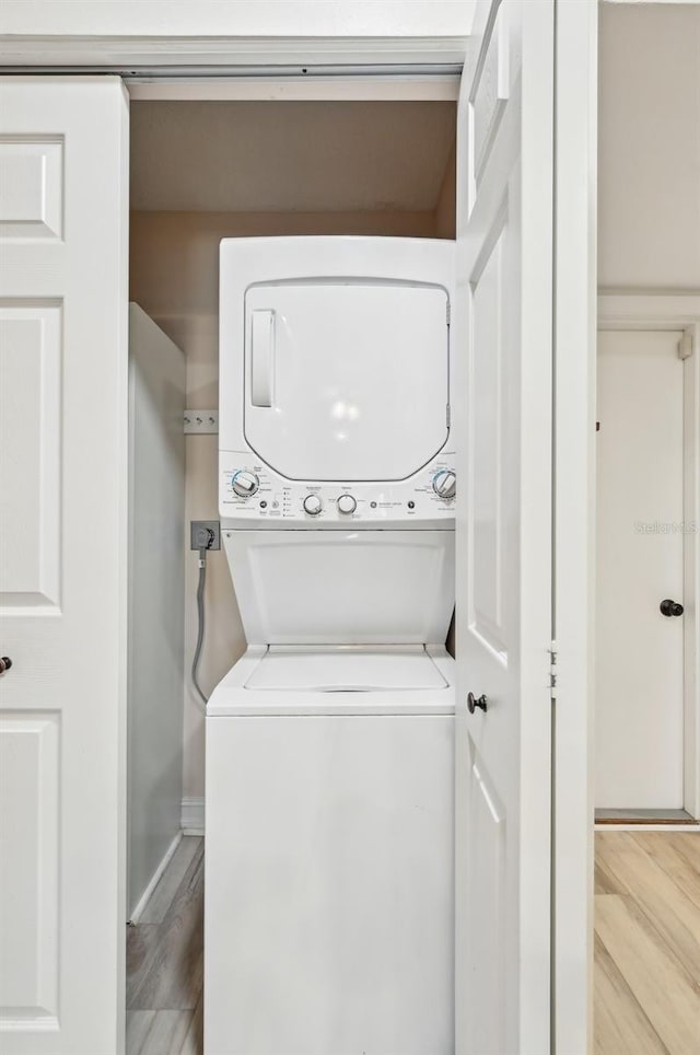 laundry room with stacked washer / dryer, laundry area, and wood finished floors