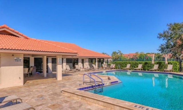 pool with a patio and fence