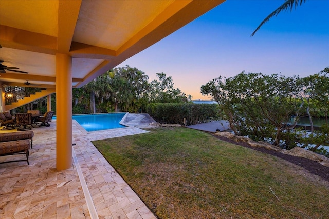 1364 Point Crisp Rd, Sarasota, FL 34242 - pool at dusk featuring a yard, an outdoor pool, a patio area, and ceiling fan