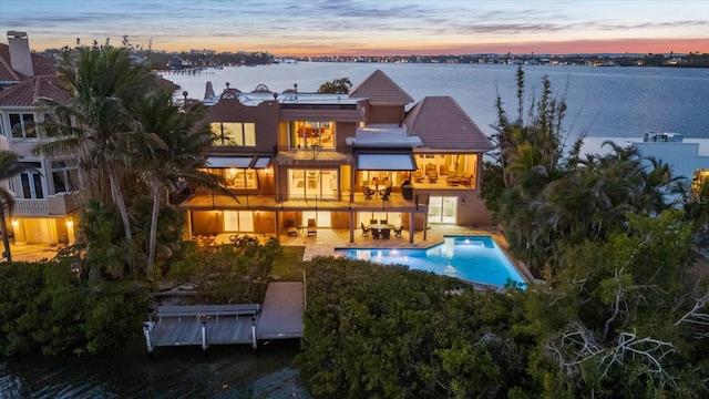 1364 Point Crisp Rd, Sarasota, FL 34242 - back of property at dusk featuring a patio area, a tile roof, stucco siding, an outdoor pool, and a balcony
