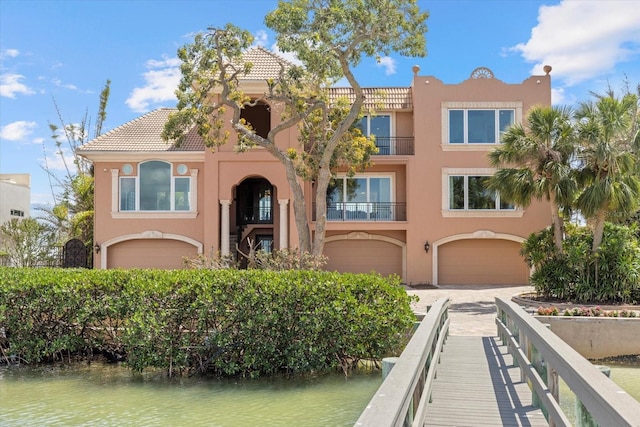 1364 Point Crisp Rd, Sarasota, FL 34242 - view of front facade with stucco siding, driveway, an attached garage, a tile roof, and a water view