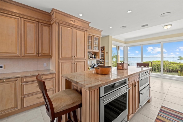 1364 Point Crisp Rd, Sarasota, FL 34242 - kitchen featuring light tile patterned floors, glass insert cabinets, stainless steel oven, a kitchen island, and light stone counters