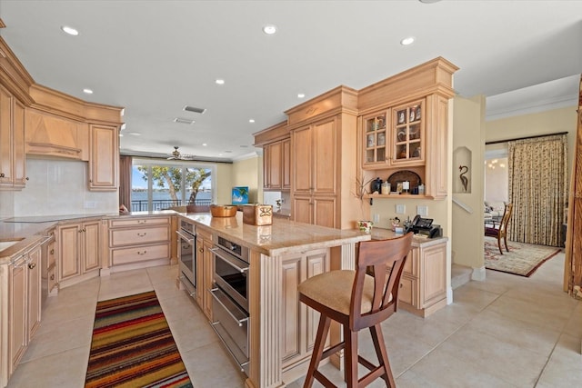 1364 Point Crisp Rd, Sarasota, FL 34242 - kitchen with light brown cabinets, a breakfast bar, crown molding, stainless steel oven, and light stone counters