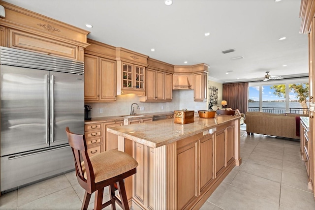 1364 Point Crisp Rd, Sarasota, FL 34242 - kitchen featuring light tile patterned floors, a ceiling fan, stainless steel built in refrigerator, light stone countertops, and visible vents