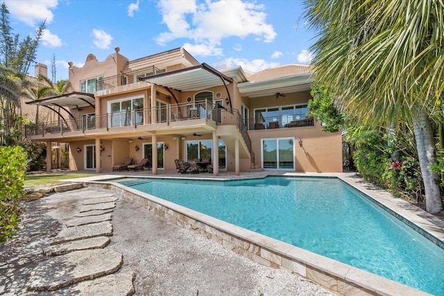 1364 Point Crisp Rd, Sarasota, FL 34242 - back of house featuring a patio area, ceiling fan, a balcony, an outdoor pool, and stucco siding