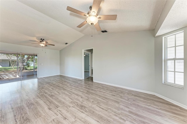 unfurnished room featuring lofted ceiling, light wood-style flooring, visible vents, and a textured ceiling