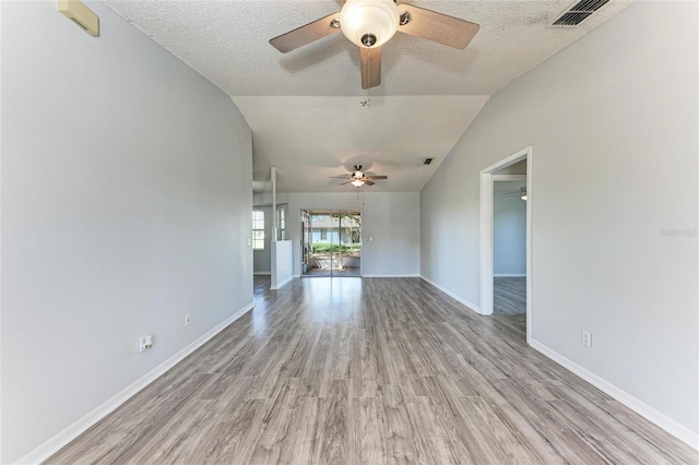 unfurnished living room with light wood finished floors, baseboards, visible vents, lofted ceiling, and a textured ceiling